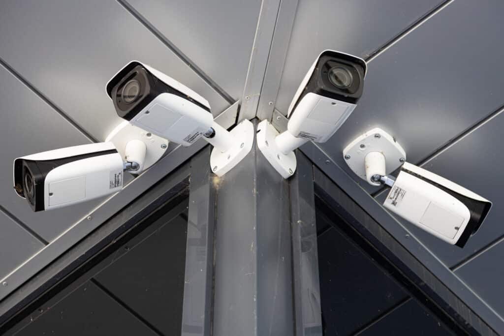 bottom view close up of four white surveillance cameras