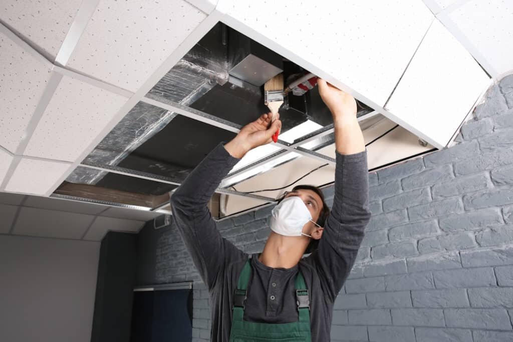 young male technician cleaning air conditioner indoors