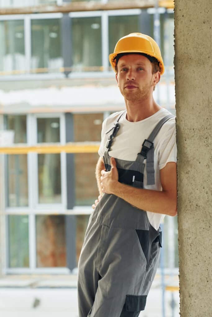 indoors in the room. young man working in uniform at construction at daytime.
