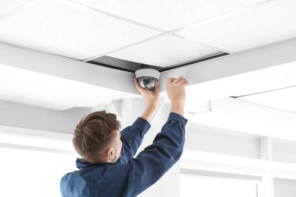 technician installing cctv camera on ceiling indoors
