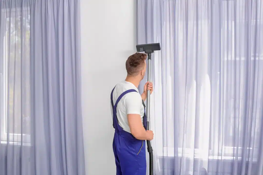 man cleaning curtains with vacuum cleaner indoors 2026 03 27 01 38 25 utc