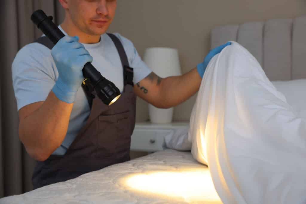 man inspecting bed with flashlight for bed bugs 2026 04 10 20 26 59 utc