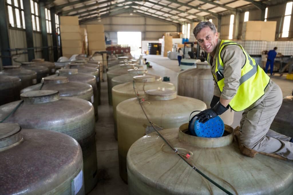 man kneeling next to large tanks in warehouse 2026 01 09 08 40 28 utc
