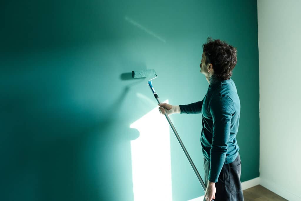 male painting teal wall in new apartment