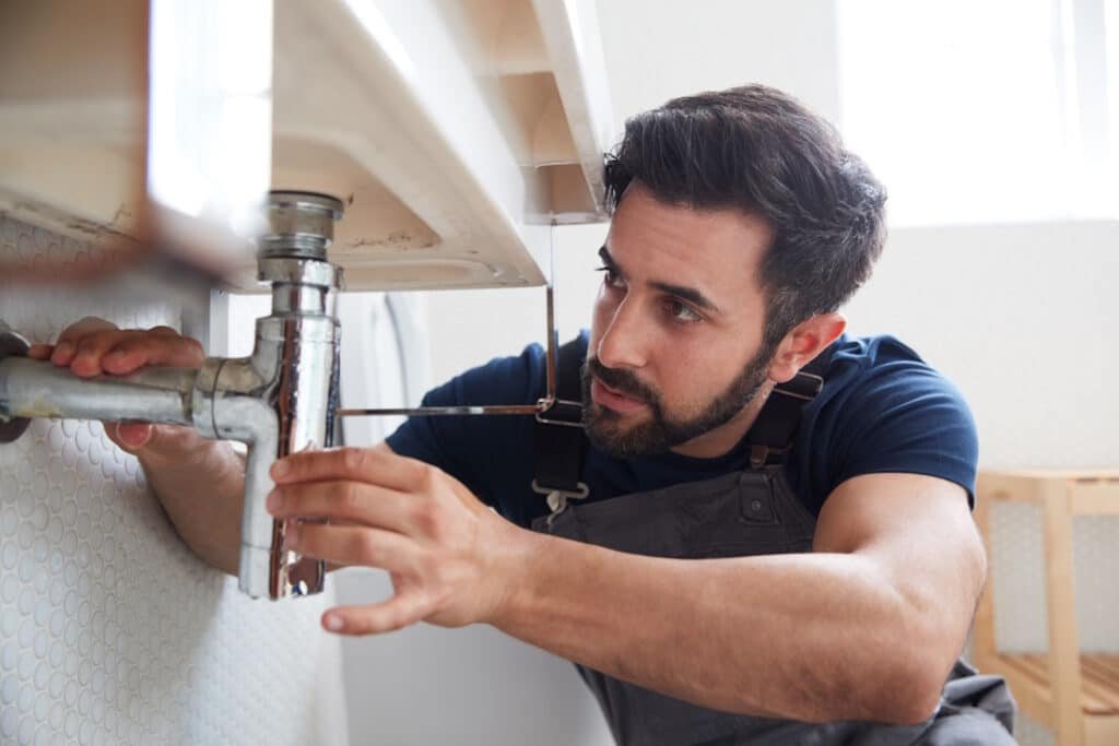 man repairing plumbing under sink in bathroom 2026 03 10 03 20 50 utc
