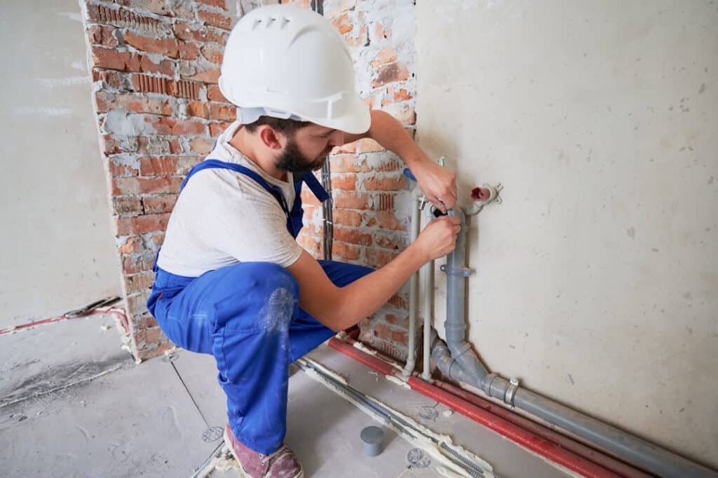 man repairs plumbing in an unfinished building 2026 03 17 01 41 35 utc
