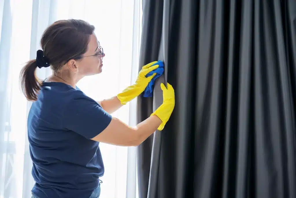 woman cleaning curtains with cloth and gloves 2026 03 16 05 12 17 utc